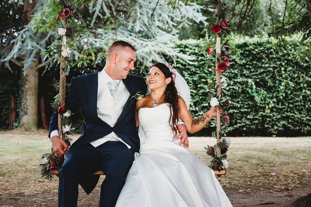 A couple staring into each others eyes smiling sat on a swing Bristol wedding photographer