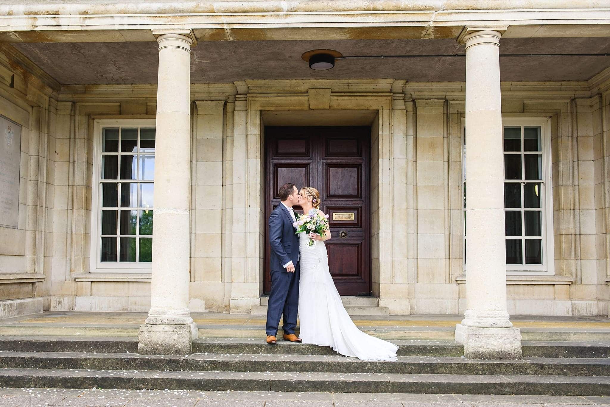 Couple kissing on the steps outside Trowbridge registry office on their wedding day