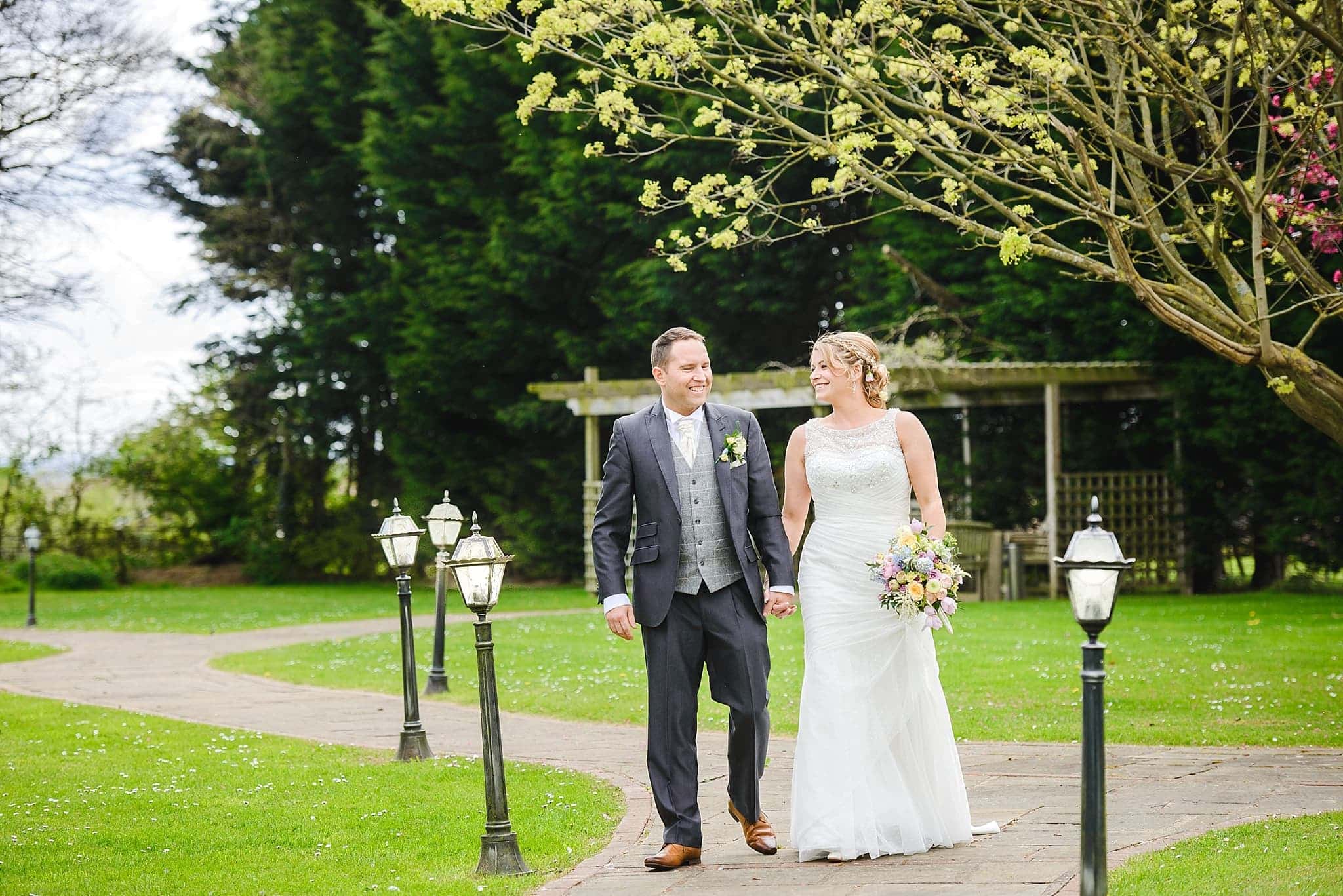Couple walking in the garden of Leigh Park hotel on their wedding day