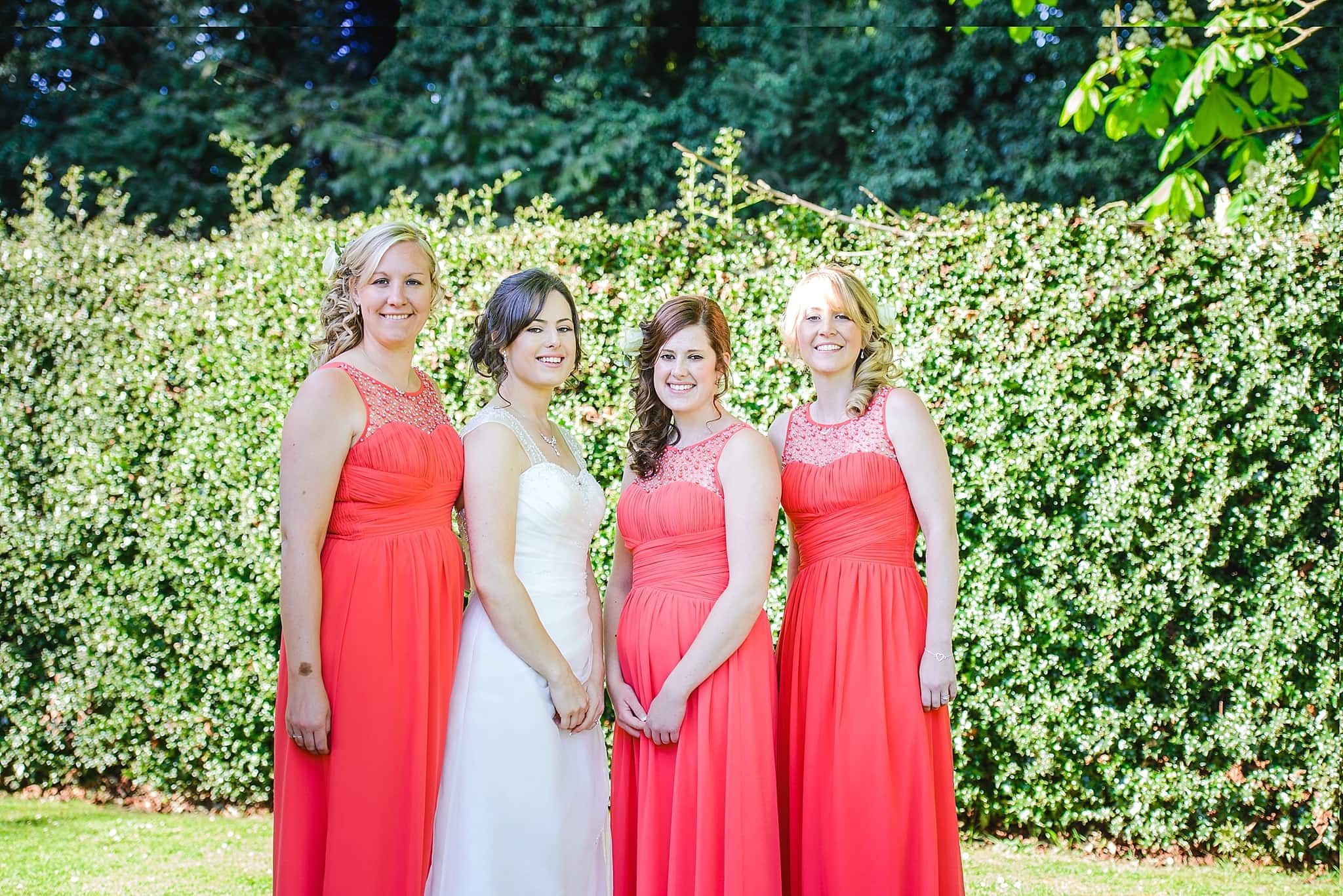 Three Bridesmaids and bride posing for a formal photo in the garden of the Hare and Hounds Tetbury