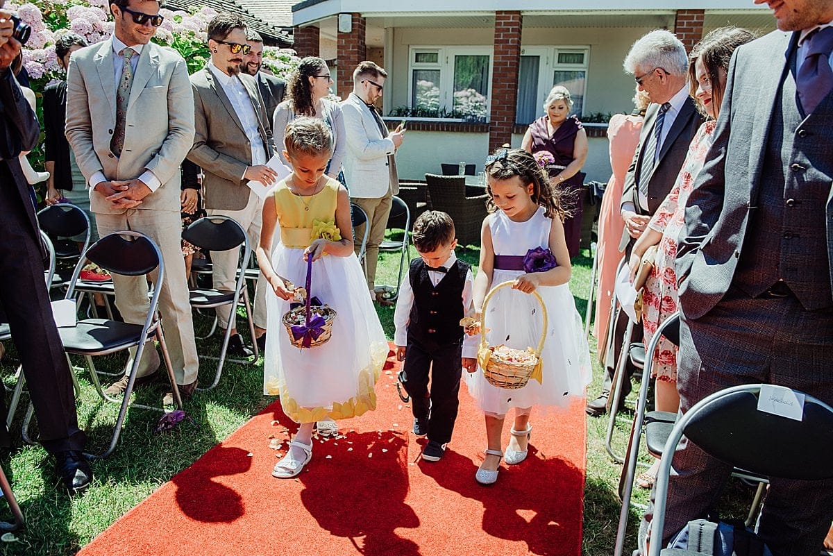 The Beachlands hotel - Weston-Super-Mare Wedding 9 two flower girls with page boy sprinkling petals on red carpet of an outdoor wedding ceremony at the Beachlands hotel WSM
