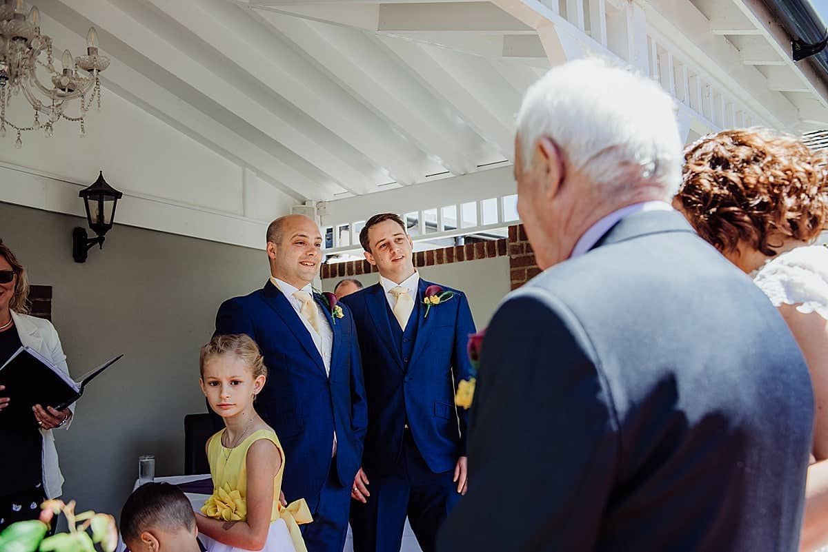 Groom and best man smiling as bride walks down the aisle at Beachlands hotel wedding