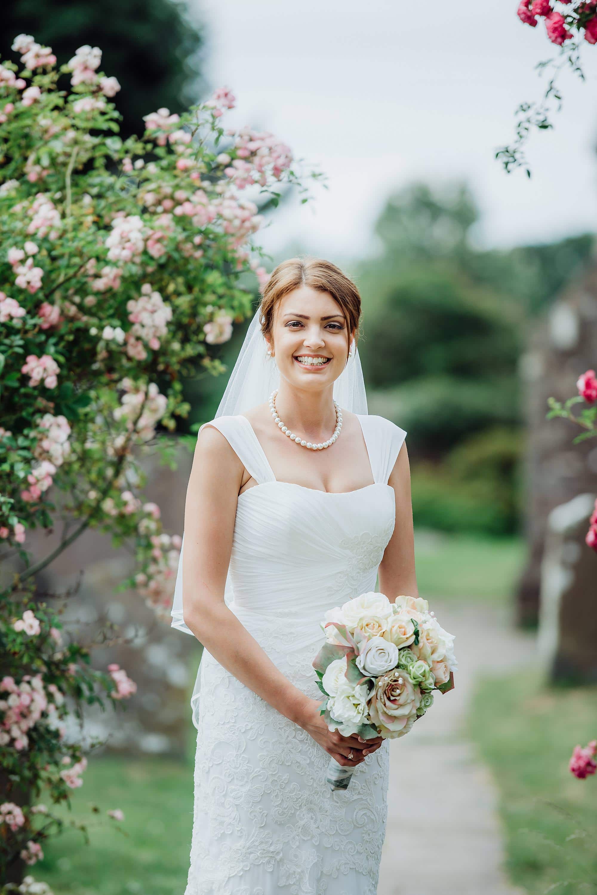 Wedding at St Michael's church Winterbourne Bristol 6 Bride stood in the garden of St Michael's church Winterbourne with beautiful flowers in the background
