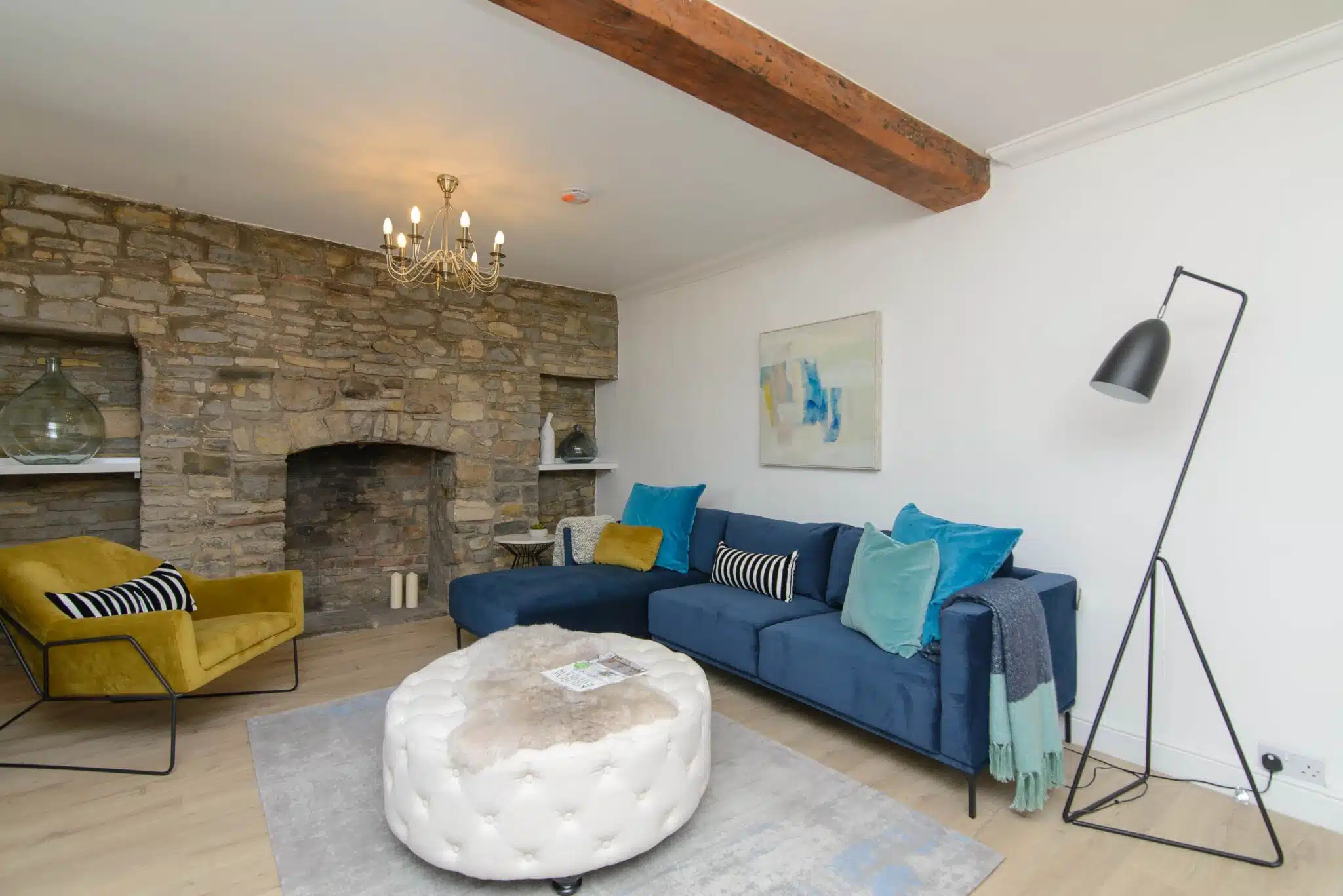 A stone wall living room cottage with blue designer sofa and yellow 