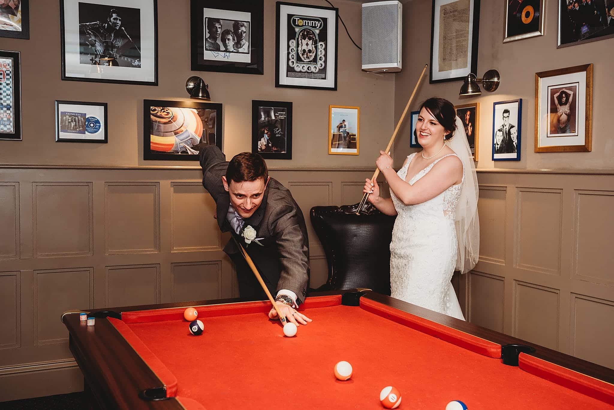 Bride and groom playfully having a game of pool in the rock room at Manor by the Lake.