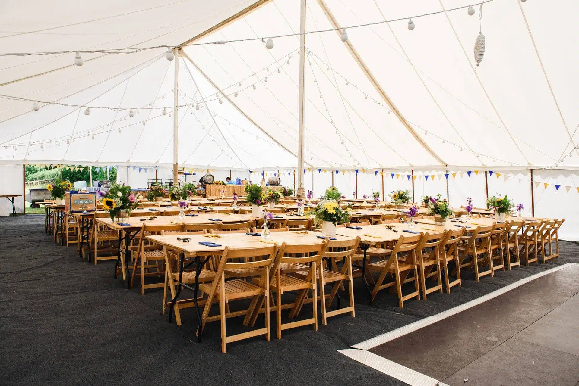 Inside of the tent with long rows of tables and chairs decorated for DIY Marquee summer wedding