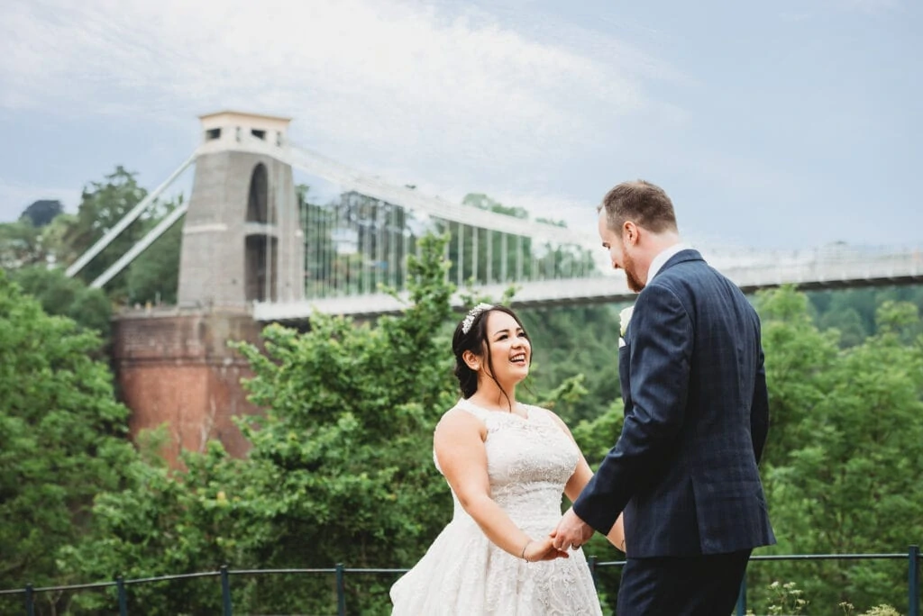 Bride and groom stood in front of the Clifton Suspension Bridge next to the Avon Gorge Hotel