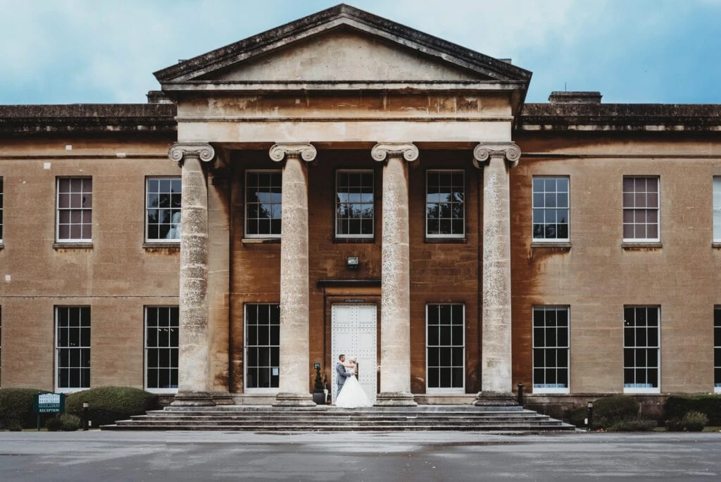 Couple stood between the columns at Leigh Court Bristol wedding venue