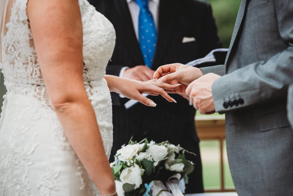 Couple exchange rings in an outdoor wedding ceremony at Orchardleigh House