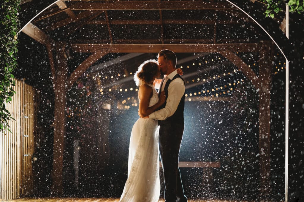 Bride and groom kiss in the rain