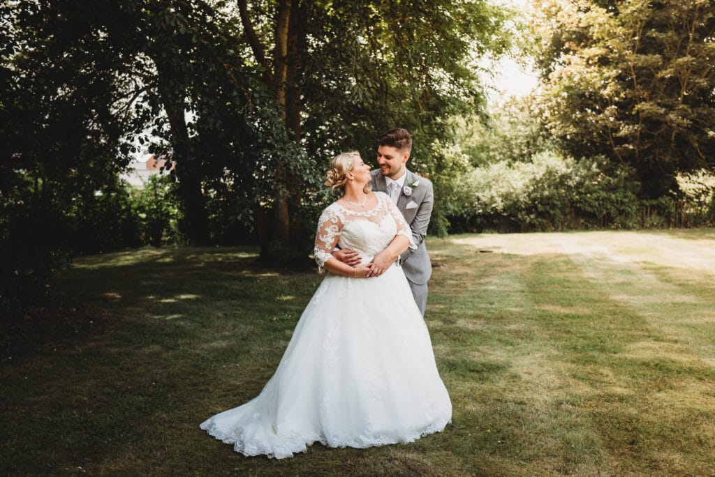 Newly married couple pose in field Wiltshire wedding photographer