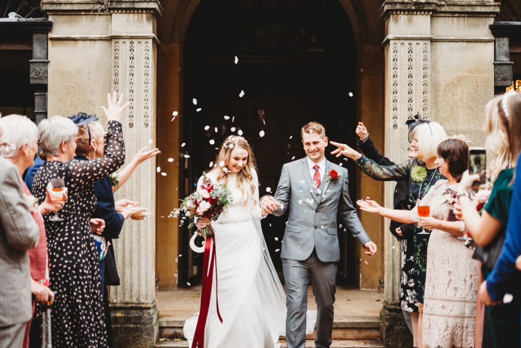 Guest throw confetti over newly weds in the garden of Coombe Lodge